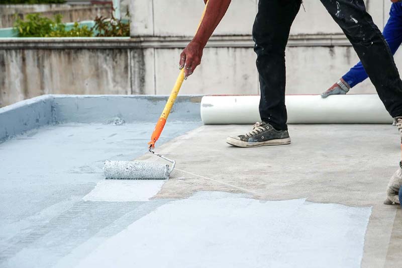Image of a worker applying a fresh coat of paint to a patio
